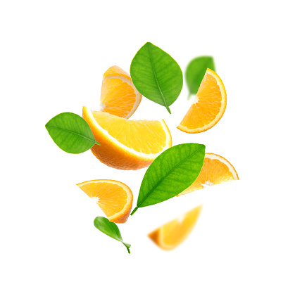 Juicy orange slices and green leaves flying on white background