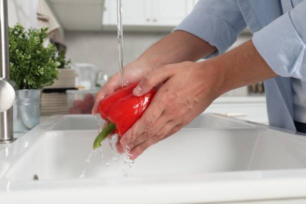 istock Man washing fresh bell pepper in kitchen, closeup 1638555584