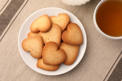 Heart shaped Danish butter cookies and tea on table, flat lay
