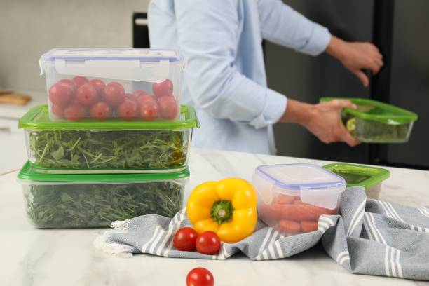 istock Glass and plastic containers with different fresh products on white marble table, selective focus. Man near fridge in kitchen 1638555626