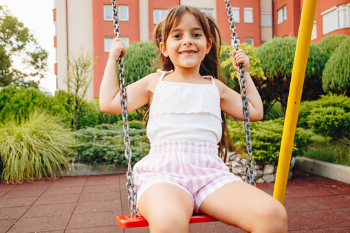 Smiling girl playing on the swing stock photo