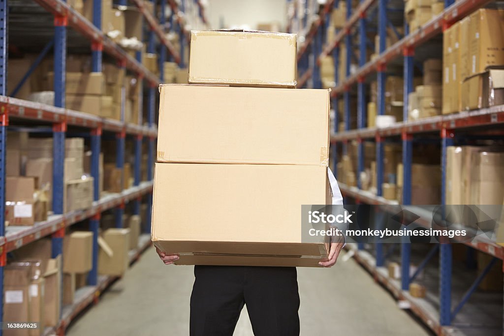 Hombre Cajas de transporte en un almacén - Foto de stock de Almacén libre de derechos