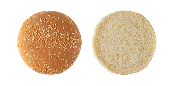 Sesame bun for burger top view isolated on white. Round bread topped with sesame seeds half cutted. Top and bottom parts separated.
