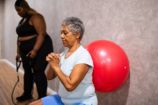 Senior woman doing squats at the gym