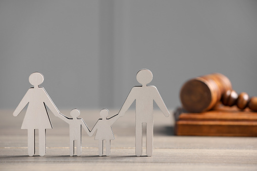 Family law. Figure of parents with children and gavel on wooden table, space for text