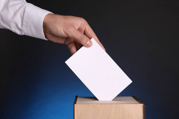 istock Man putting his vote into ballot box on dark blue background, closeup 1638752575