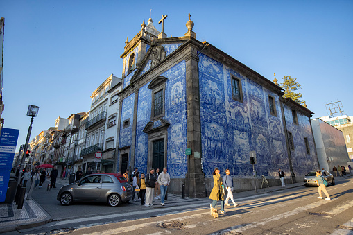 Street view of  Chapel of Souls in the moring, Porto, Portugal. Many people and cars can be seen outside in the street.