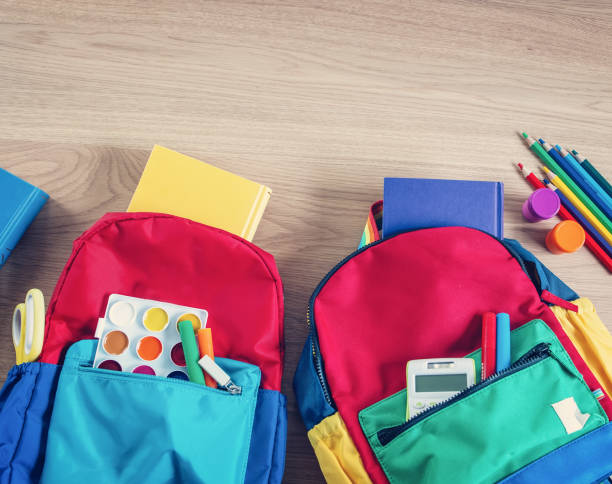 istock Colourful backpacks lying on the table filled by notebooks and stationery. 1638771975