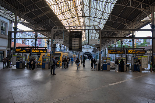 Interior view of Sao Bento railway station, Porto, Portugal. Travelers and trains can be seen in the platform.