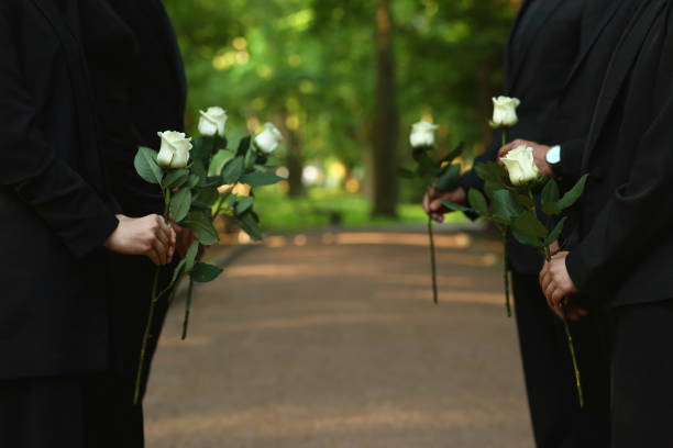 istock People with white rose flowers outdoors, closeup. Funeral ceremony 1638779046