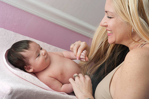 Mother and baby girl at changing table stock photo