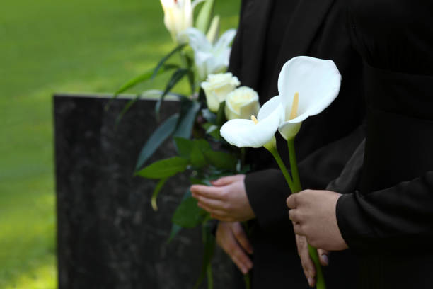 istock People with flowers outdoors, closeup. Funeral ceremony 1638779487