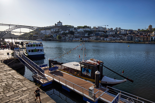 Boats and Douro river in the Ribeira, Porto, Portugal. Dom Luis I Bridge and Vila Nova de Gaia district in the background.