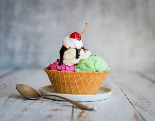 Ice cream sundae in a waffle bowl on weathered wood table.