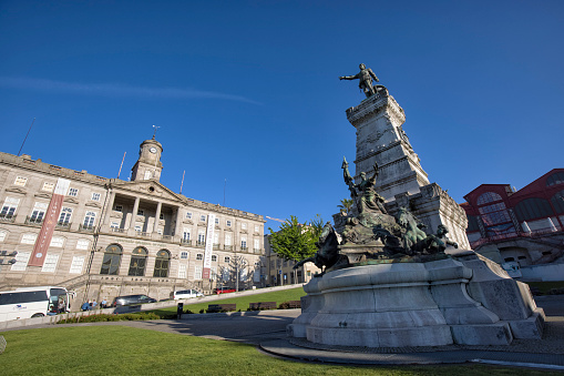 Street view of historic Ribeira district in the morning, Porto, Portugal. The statue of Prince Henry the Navigator and Palácio da Bolsa (Stock Exchange Palace) in the picture.