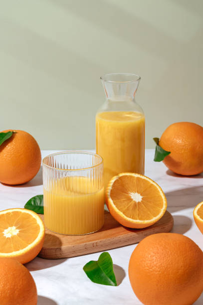 グラスとデカンタに入った新鮮なオレンジジュース。テーブルの上のオレンジ - juice carafe glass decanter ストックフォトと画像