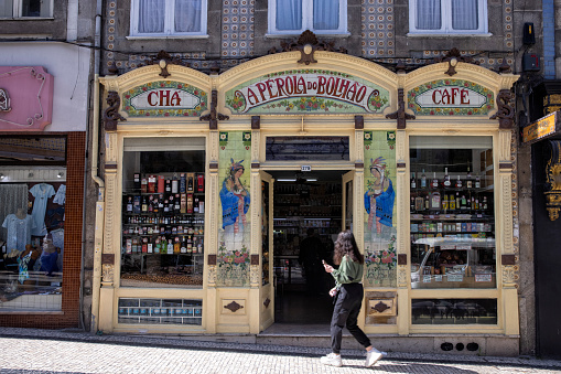 Exterior view of Aperola do Bolhao coffee and tea shop, Porto, Portugal. A woman walking by the entrance.