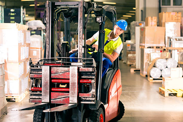 forklift driver at warehouse of forwarding forklift driver in protective vest driving forklift at warehouse of freight forwarding company forklift photos stock pictures, royalty-free photos & images