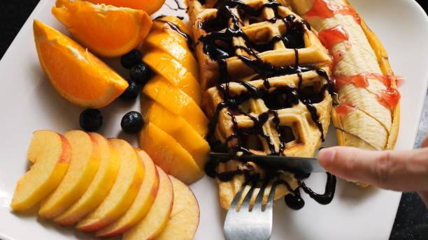 Indulge in Viennese Waffles Breakfast: Chocolate-Drenched Waffles and Fresh Fruits. Explore the delightful morning scene featuring waffles smothered in chocolate syrup and an array of fresh fruits