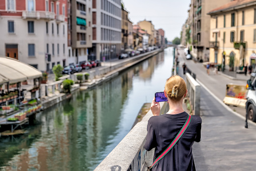 Milan, Italy - July 2, 2022: A blonde woman taking in the sights and snapping a photo of the Canal District in Milan
