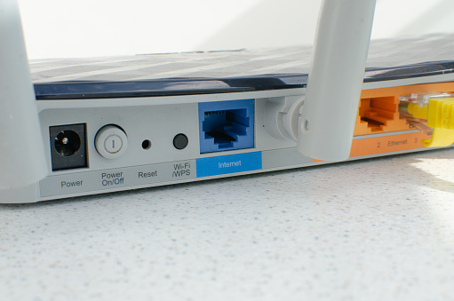 Close-up detail of a modern Wi-Fi router, with multiple inputs and ports for cable connections, representing internet technology and connections