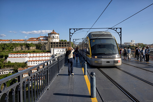 Metro train on Dom Luis I bridge over Douro river, Porto, Portugal. Hills of Vila Nova de Gaia and Serra do Pilar Monastery in the background.