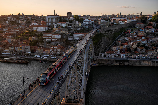 Aerial view cityscape over Douro river at sunset, Porto, Portugal. Metro train travelling across the Dom Luis I bridge and colorful buildings at the old district of Ribeira.