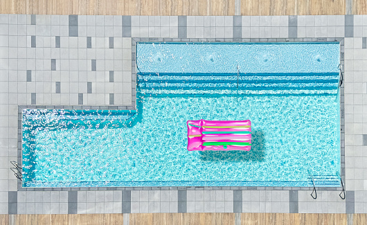 Looking down on a large, chic pool from a high point of view with a floating lilo