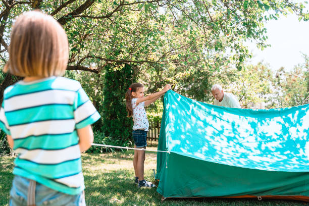 happy children and grandfather setting up tent tent. garden party. summer fun. child. - camping tent offspring 60s imagens e fotografias de stock