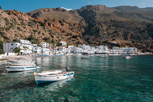 Loutro, Crete - May 17, 2023:  Small boats float on clear, emerald waters of the sea in the picturesque, white-washed village of Loutro, Crete.