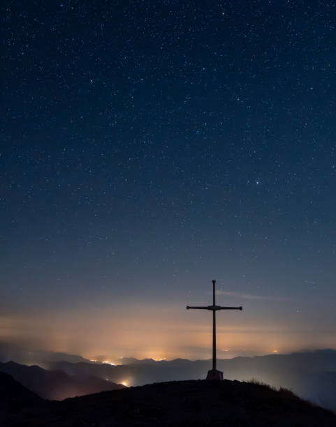istock cross on a mountain at night with lights and stars 1638991061
