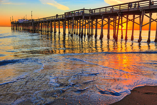 The Balboa Pier in Orange County, California Incoming tide reflects the sunsent at Balboa Pier in Newport Beach, CA newport beach california stock pictures, royalty-free photos & images