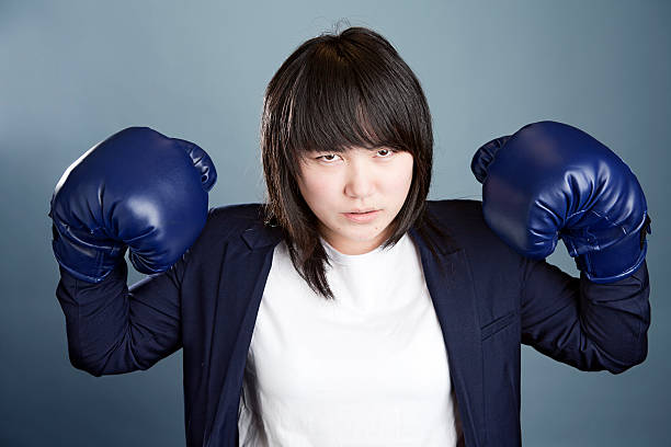 femme d'affaires dans les gants de boxe - women business strength boxing photos et images de collection