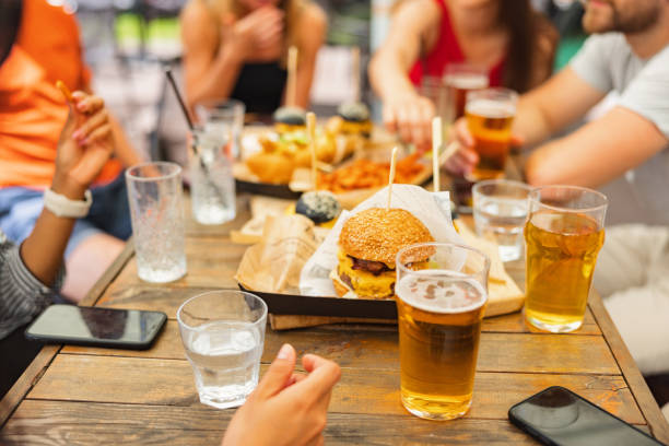 istock Frontal View Of A Wooden Table With Delicious Snacks And Beverages Surrounded By A Multi-Racial Group 1639020770