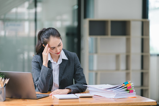 Professional millennial Accountant Woman in casuals working on financial analysis documents with a tense expression in the office