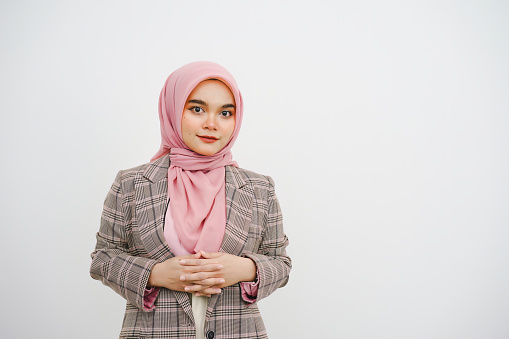 Studio portrait of beautiful young muslim businesswoman pink hijab smiling at camera on white background