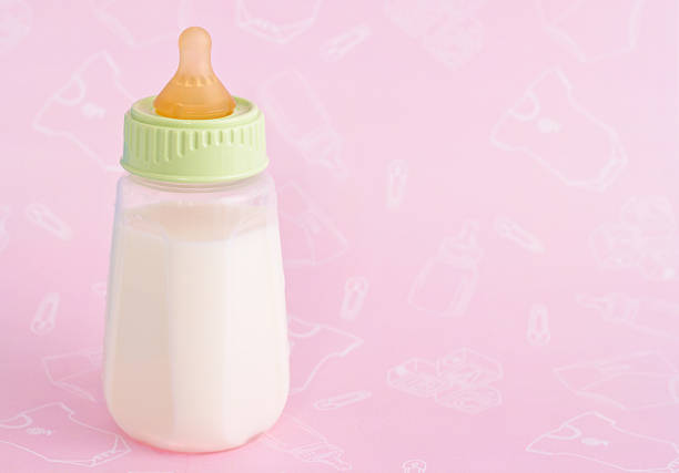 Bottle of milk for baby on pink background. Milk heart shape, Top view