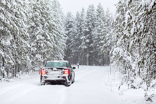 veicolo terrestre nero in piedi su una strada di campagna nivea - rear view winter blizzard nordic countries foto e immagini stock