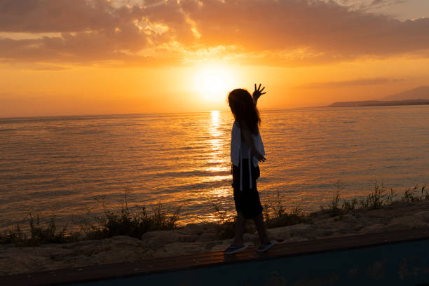 Girl standing on beach at sunset.