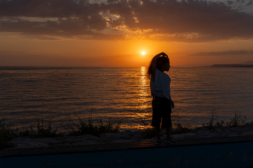Girl standing on beach at sunset.