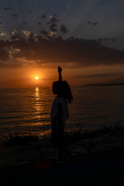 istock Girl standing on beach at sunset. 1639158969