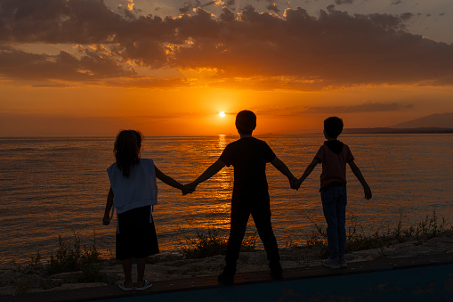 Children standing on beach at sunset.