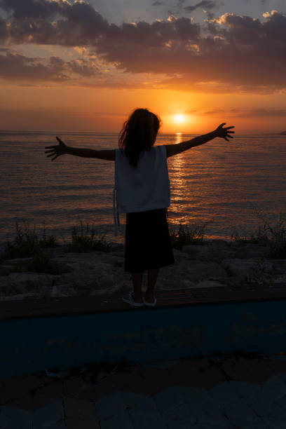 Girl standing on beach at sunset.