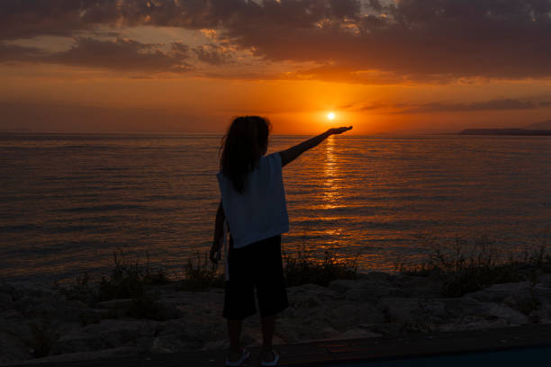 Girl standing on beach at sunset.