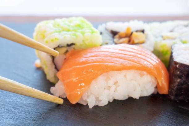 istock Close-up of chopsticks picking up salmon sushi. Selective focus 1639176986