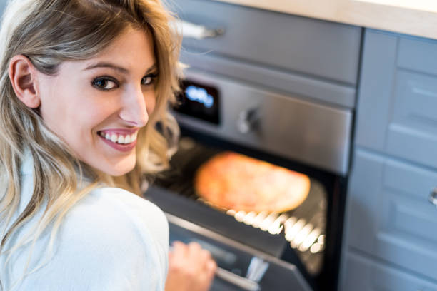 istock young woman taking a pizza from the oven 1639199326