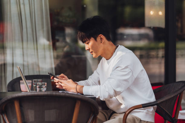 istock Young man at coffee shop using mobile phone 1639246801