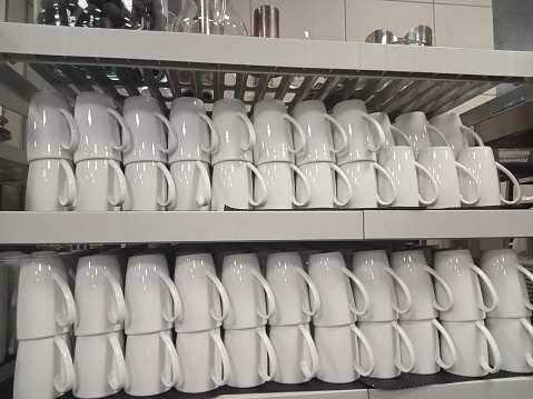 cups or mugs lined up neatly on the shelf.