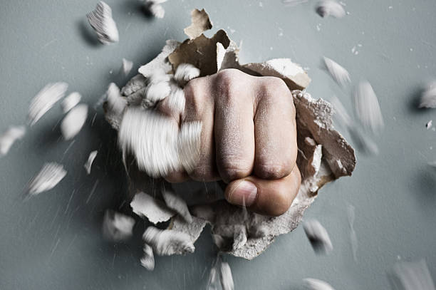 fist a wall is broken through by a fist rough hands man stock pictures, royalty-free photos & images