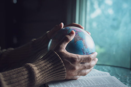 Man holding the globe and praying for people around the world.